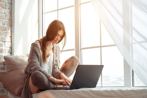 Girl using laptop in front of the window Stock Photo