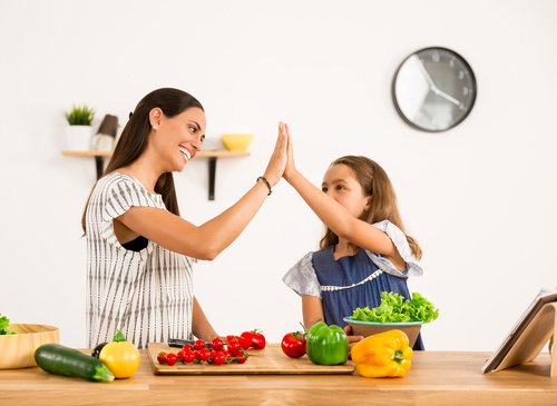 Happy mother and daughter in the kitchen clap Stock Photo