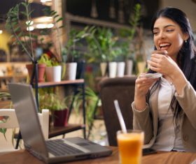 Lady eating afternoon tea looking at computer video Stock Photo