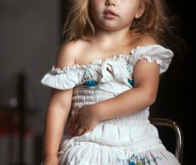 Little girl sitting on metal chair Stock Photo