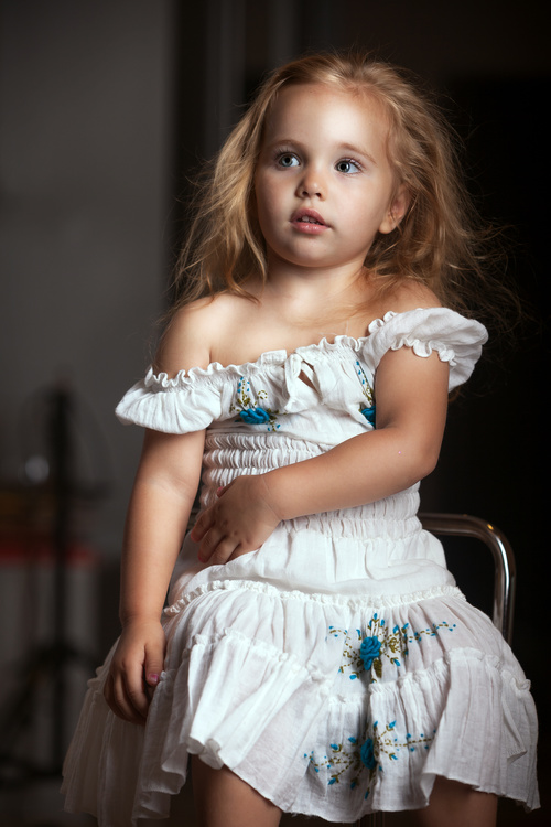 Little girl sitting on metal chair Stock Photo