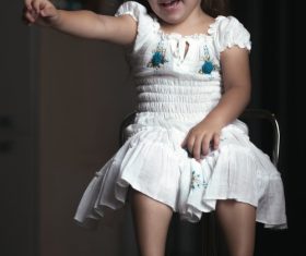 Little girl wearing moms high heels sitting on metal chair Stock Photo 01