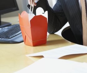 Man eating fast food in office Stock Photo