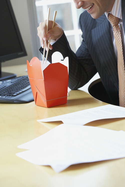 Man eating fast food in office Stock Photo