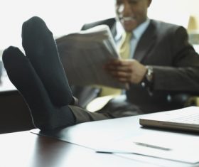 Man in office relaxing reading newspaper Stock Photo