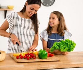 Mom teach her daughter cutting vegetables in the kitchen Stock Photo 01