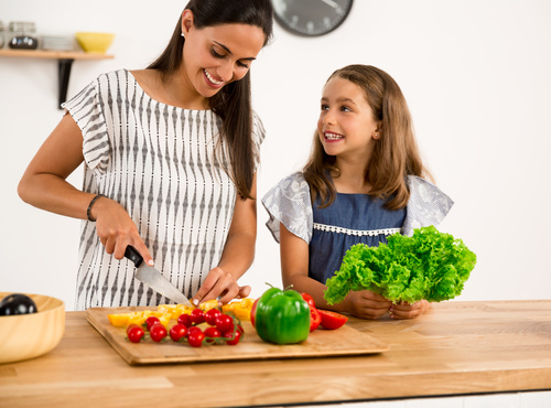 Mom teach her daughter cutting vegetables in the kitchen Stock Photo 01
