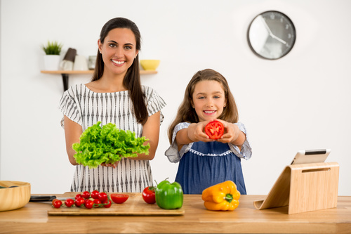 Mother and daughter holding fresh vegetables Stock Photo
