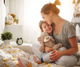 Mother sitting on bed holding her baby Stock Photo