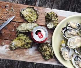 Oysters and drinks on chopping board Stock Photo