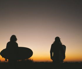 People carrying surfboard in dark dusk Stock Photo