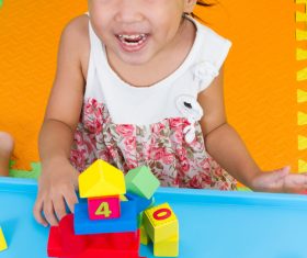 Smiling little girl playing with building blocks Stock Photo