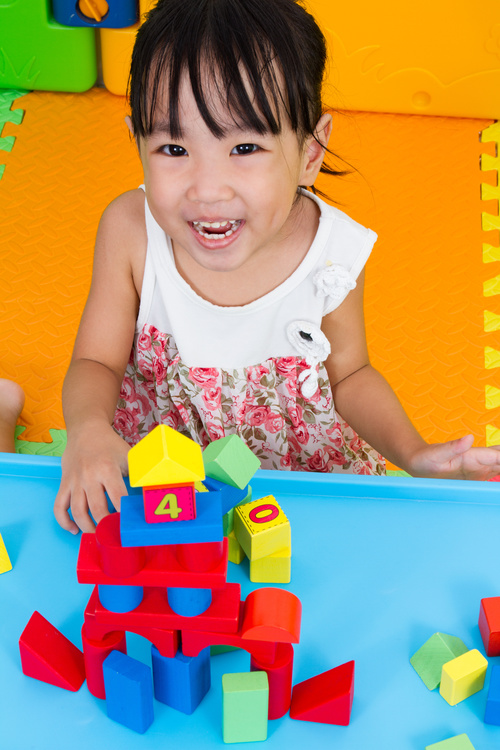 Smiling little girl playing with building blocks Stock Photo