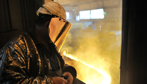 Steel workers view molten iron Stock Photo