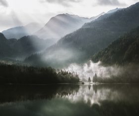 Sun rays on calm lake mountain scenery Stock Photo
