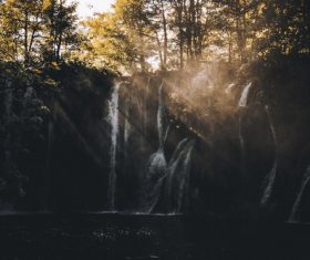 Sun rays on wild waterfall scenery Stock Photo