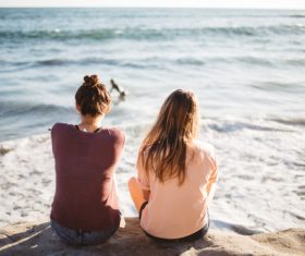 Two girls sitting at the seaside Stock Photo