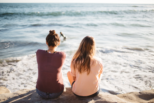 Two girls sitting at the seaside Stock Photo