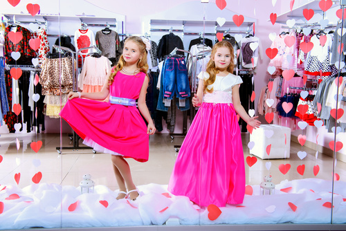 Two little girls try on clothes in front of the mall mirror Stock Photo
