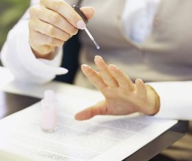 Woman applying nail polish in the office Stock Photo