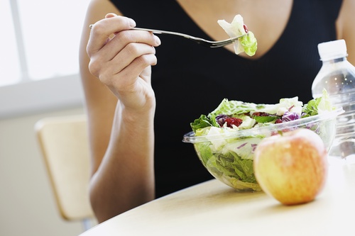 Woman eating salad and apple for lunch Stock Photo