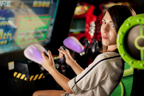 Woman playing shooting game in playroom Stock Photo