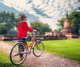 Woman pushing bicycle looking at ancient architecture Stock Photo