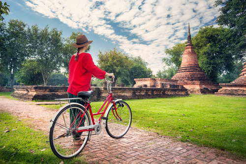 Woman pushing bicycle looking at ancient architecture Stock Photo