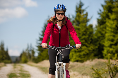 Woman wearing hardhat riding bicycle Stock Photo