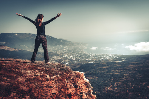 Woman with arms outstretched on the top of the mountain Stock Photo