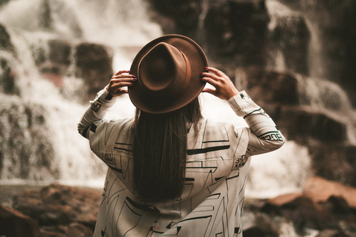 Woman with hat looking at waterfall Stock Photo