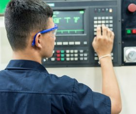 Workers manipulate digitally controlled machine tools Stock Photo