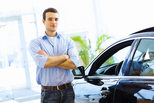Young man standing next to new car Stock Photo