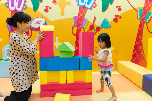 little girl and her mother together to build blocks Stock Photo