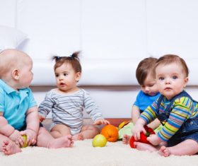 Baby sitting on the carpet playing Stock Photo