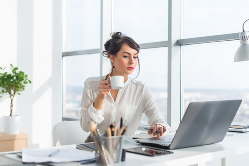 Business woman drinking coffee using laptop Stock Photo