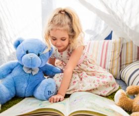 Child and teddy bear reading book together Stock Photo