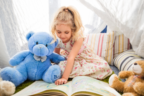 Child and teddy bear reading book together Stock Photo