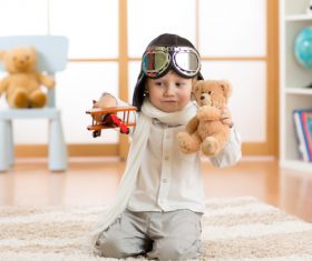 Child holding teddy bear play wooden plane Stock Photo 01