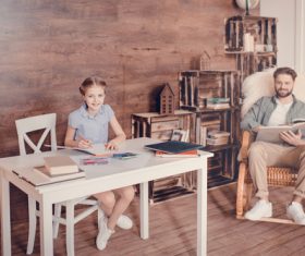Father reading book and daughter doing homework Stock Photo