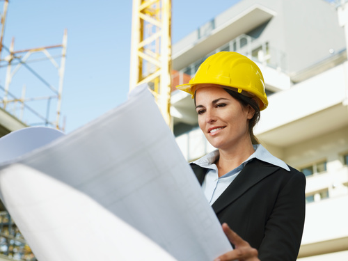 Female engineer looking at drawings at construction site Stock Photo
