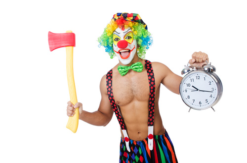 Funny clown holding an axe and alarm clock Stock Photo
