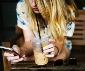 Girl holding drink and playing with mobile phone Stock Photo