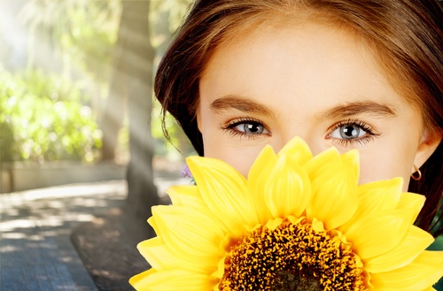 Girl holding sunflower flower covering face Stock Photo