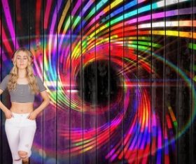 Girl standing in front of a colorful background wall wearing headphones Stock Photo