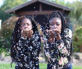 Good sisters blowing paper flowers Stock Photo