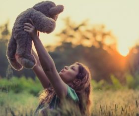 Joyful woman with teddy bear under sunlight Stock Photo