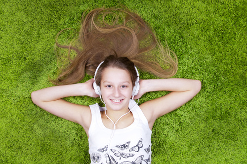 Little girl lying on the carpet listening to music Stock Photo