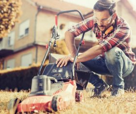 Man cleans the hand-push lawn mower Stock Photo 01