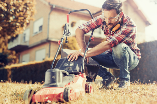 Man cleans the hand-push lawn mower Stock Photo 01